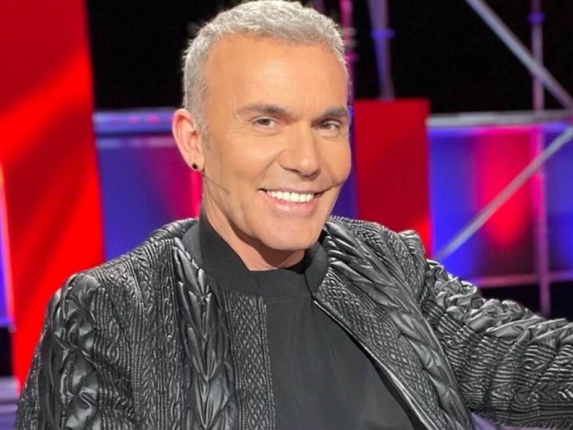 Στέλιος Ρόκκος στο δωμάτιο του νοσοκομείου μετά την περιπέτεια υγείας του με εμβολή, καθισμένος σε ένα κρεβάτι κρατώντας ένα μήνυμα για τους θαυμαστές του